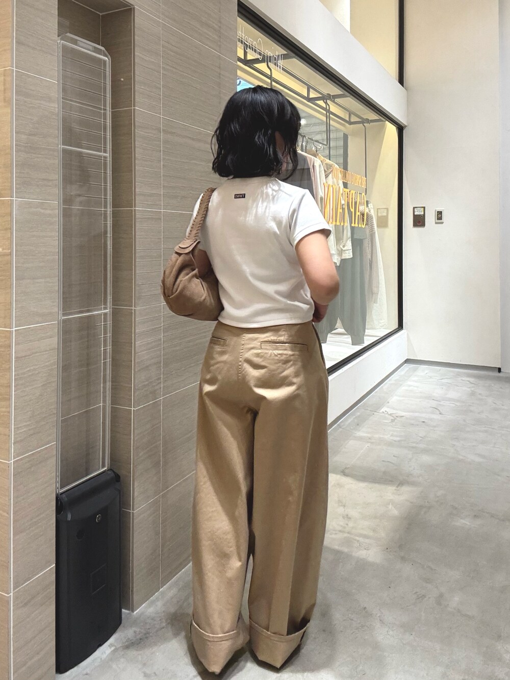 ベージュ系のチノパンツ、ホワイト系のTシャツ/カットソー、ブラウン系のショルダーバッグを着用したレディースの冬コーディネートの4枚目の写真