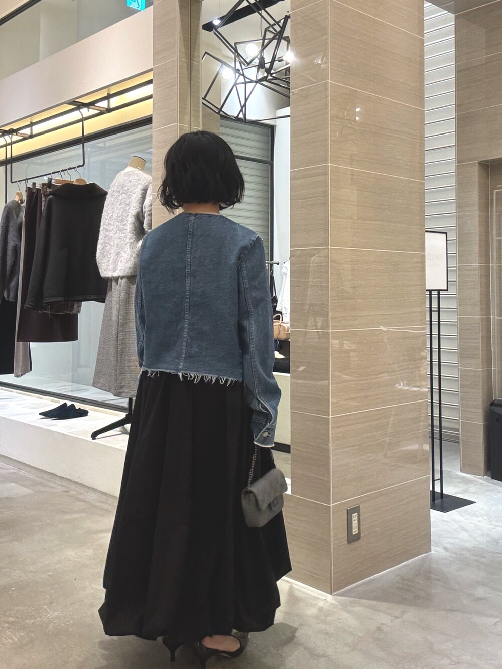 ブルー系のデニムジャケット、ブラック系のスカート、グレー系のショルダーバッグを着用したレディースの冬コーディネートの4枚目の写真