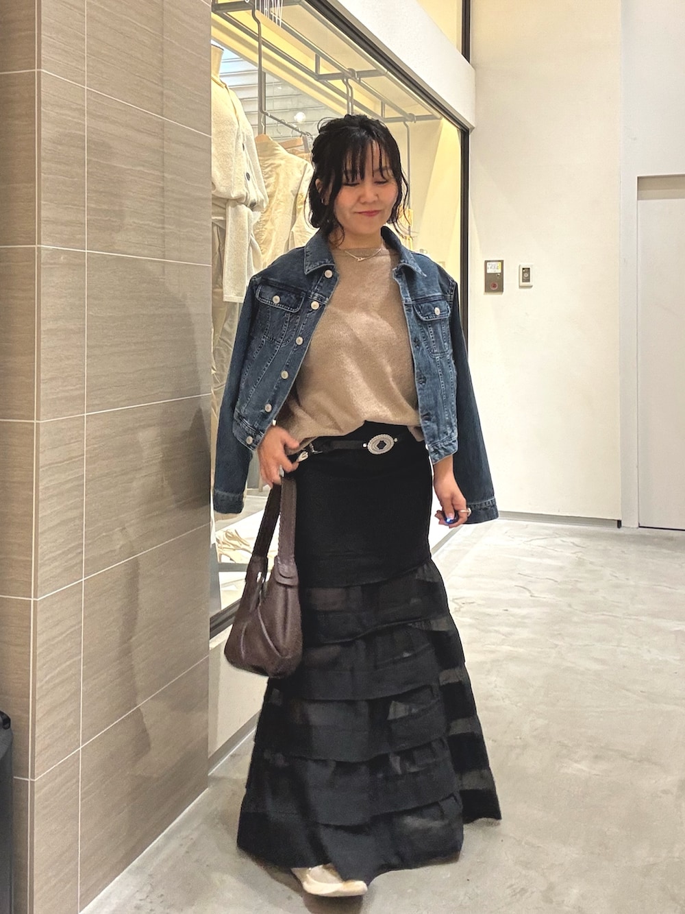 ブラック系のスカート、ブラウン系のショルダーバッグ、ブルー系のデニムジャケットを着用したレディースの冬コーディネートの2枚目の写真