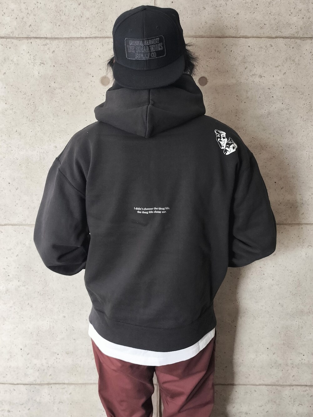 ブラック系のパーカー、ブラウン系のチノパンツ、ブラック系のキャップを着用したメンズの秋コーディネートの2枚目の写真