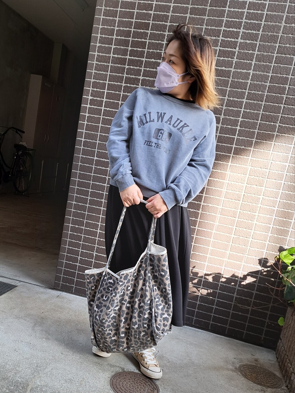 ブルー系のスウェット、ブラック系のワンピース、ブラウン系のトートバッグを着用したレディースの秋コーディネートの2枚目の写真