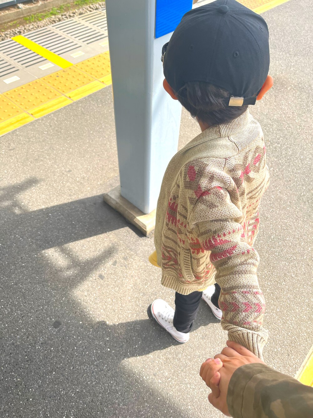 ブラウン系のニット/セーター、イエロー系のTシャツ/カットソー、ブラック系のパンツを着用したレディースの春コーディネートの2枚目の写真