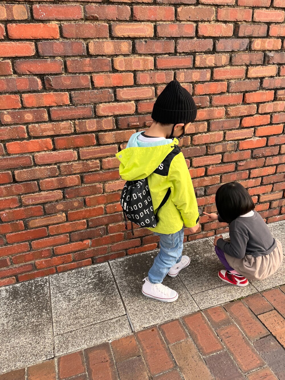 イエロー系のナイロンジャケット、ブルー系のデニムパンツ、ホワイト系のスニーカーを着用したレディースの春コーディネートの2枚目の写真