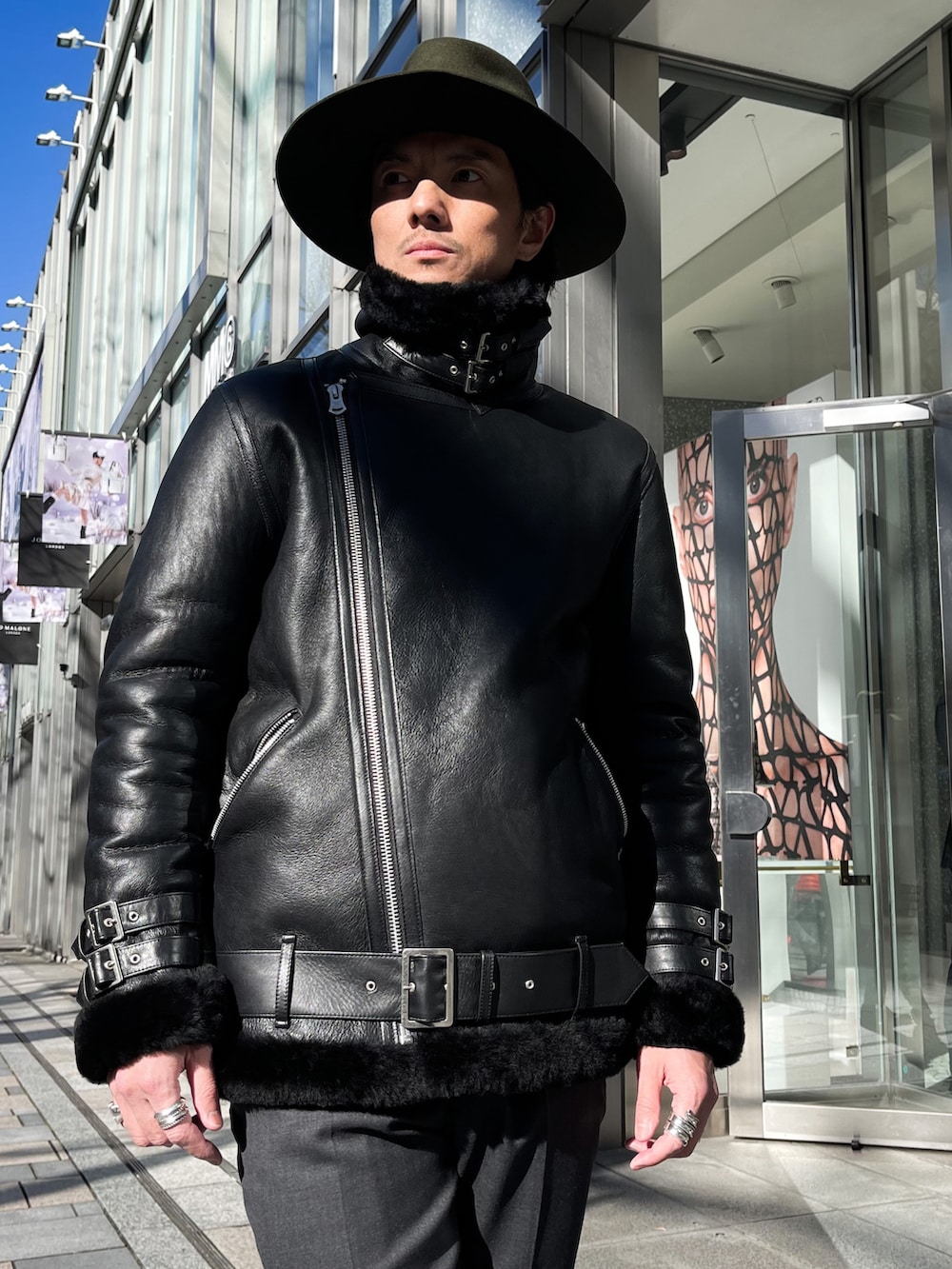 ブラック系のムートンコート、グレー系のスラックス、ブラック系のブーツを着用したメンズの冬コーディネートの2枚目の写真