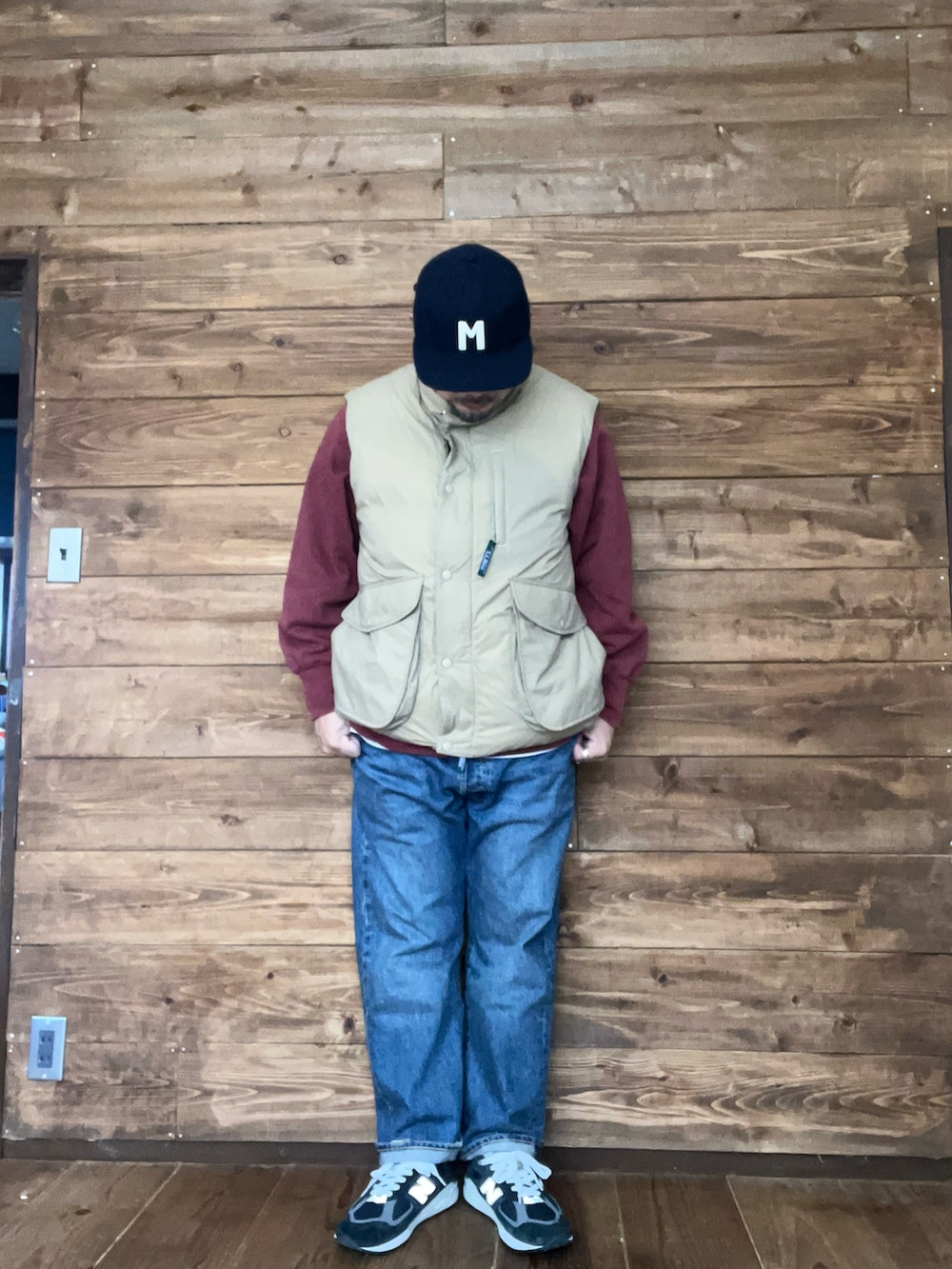 ベージュ系のダウンベスト、ブルー系のスニーカー、ブルー系のキャップを着用したメンズの冬コーディネートの2枚目の写真