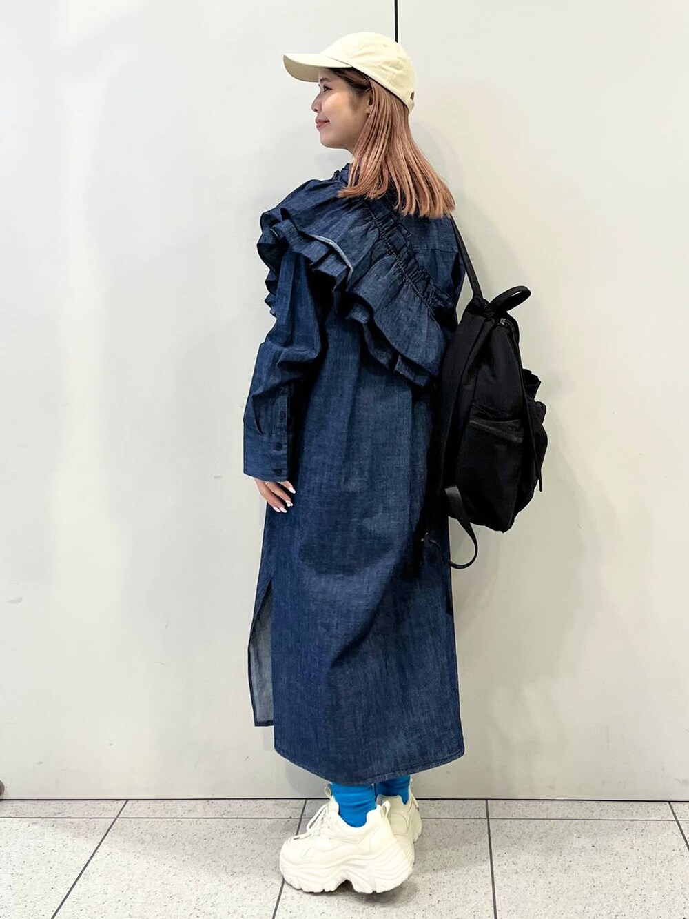 ホワイト系のスニーカー、ブラック系のバックパック/リュック、ブルー系のワンピースを着用したレディースの冬コーディネートの4枚目の写真