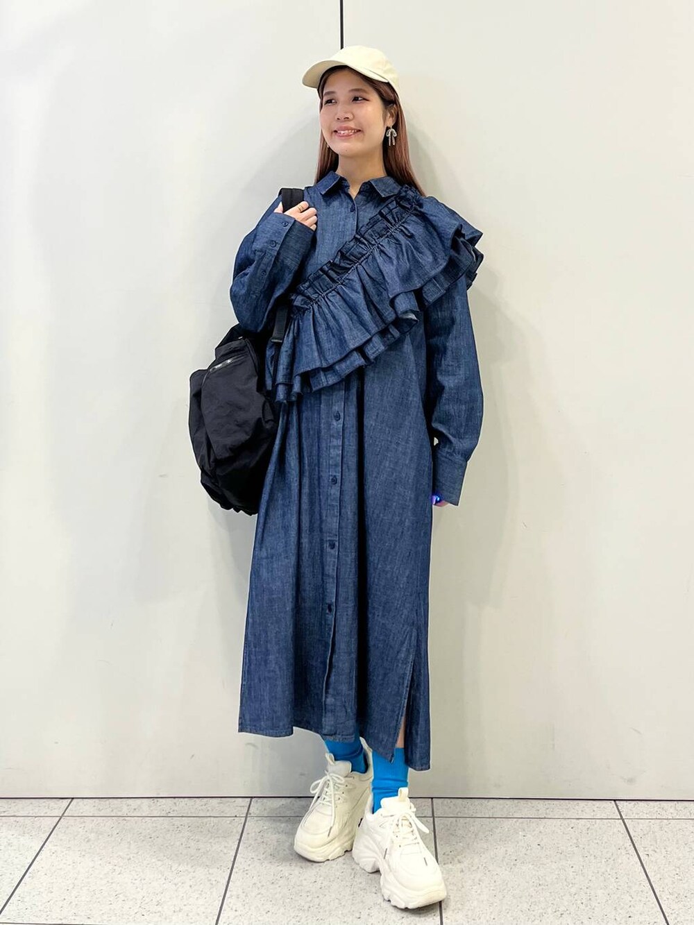 ホワイト系のスニーカー、ブラック系のバックパック/リュック、ブルー系のワンピースを着用したレディースの冬コーディネートの2枚目の写真