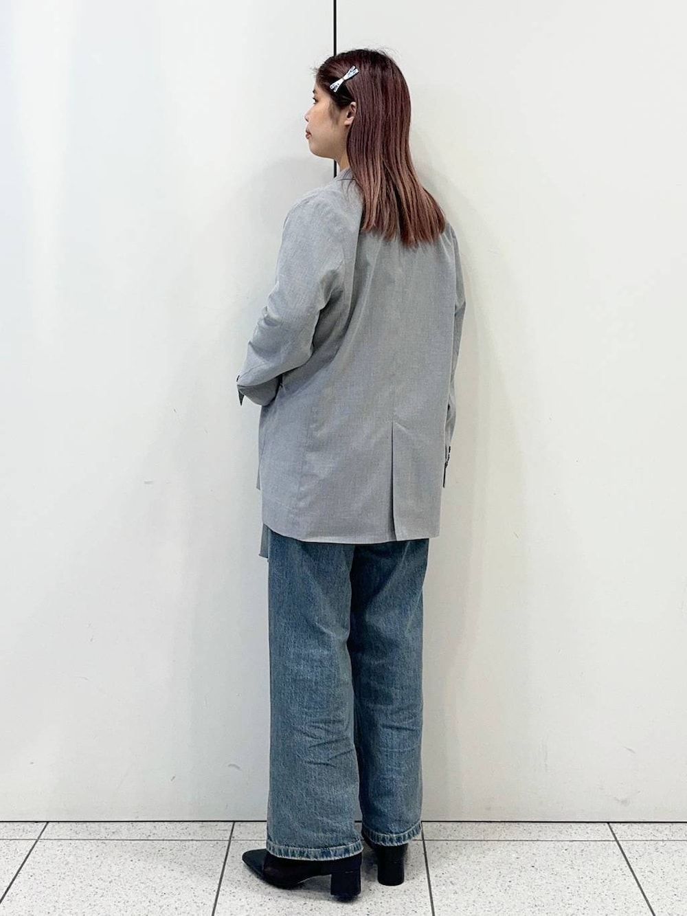 ブラック系のブーツ、ブルー系のデニムパンツ、グレー系のテーラードジャケットを着用したレディースの春コーディネートの4枚目の写真