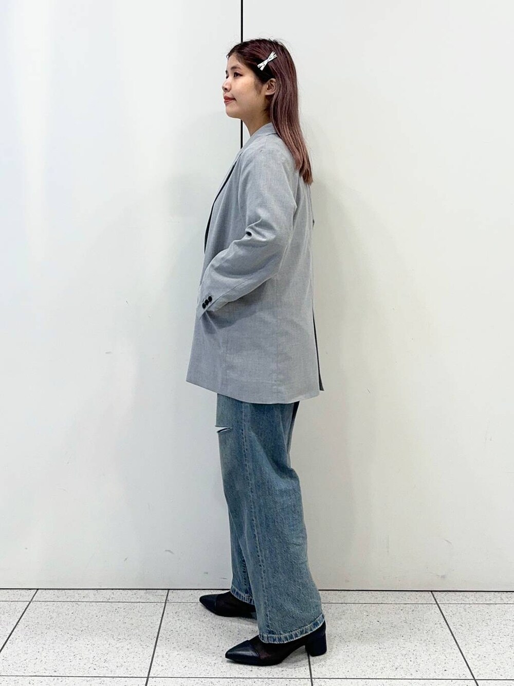 ブラック系のブーツ、ブルー系のデニムパンツ、グレー系のテーラードジャケットを着用したレディースの春コーディネートの3枚目の写真