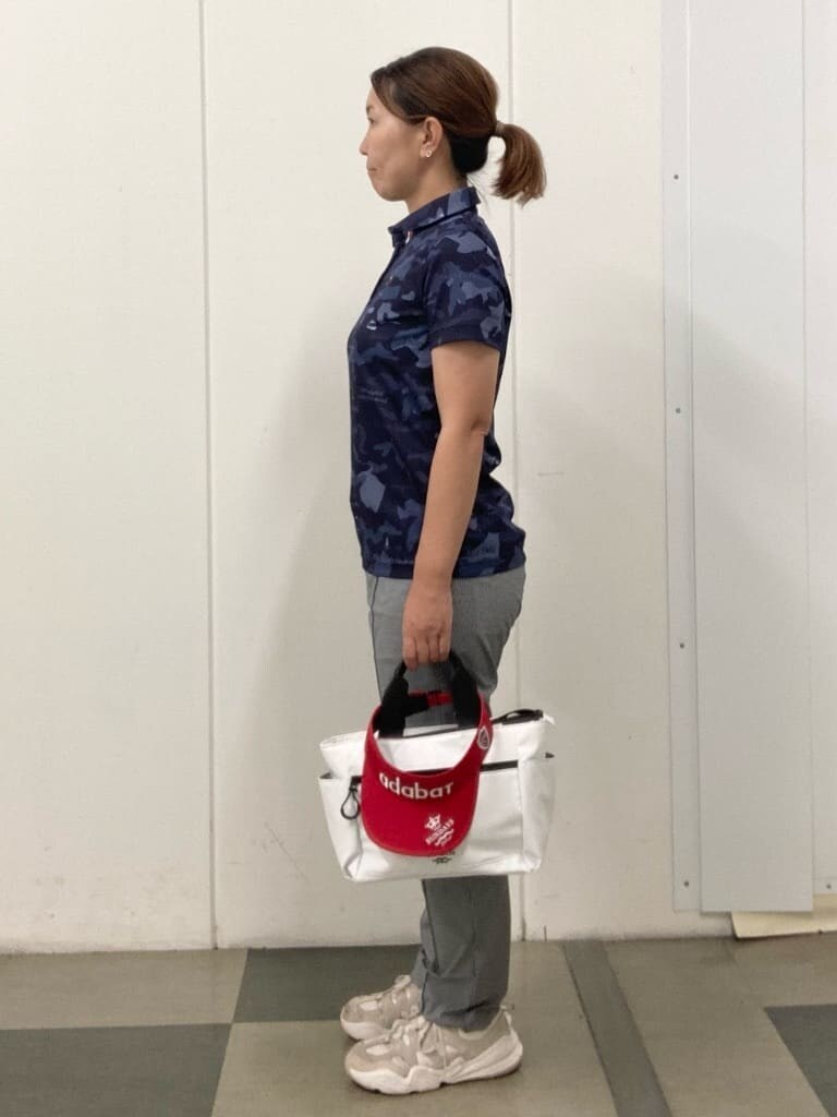 ブルー系のポロシャツ、ホワイト系のハンドバッグ、レッド系のサンバイザーを着用したレディースの夏コーディネートの2枚目の写真