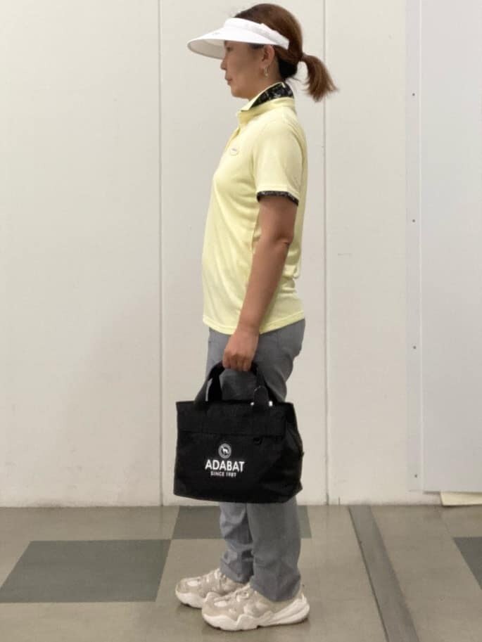 イエロー系のポロシャツ、ホワイト系のその他パンツ、ブラック系のハンドバッグを着用したレディースの春コーディネートの2枚目の写真