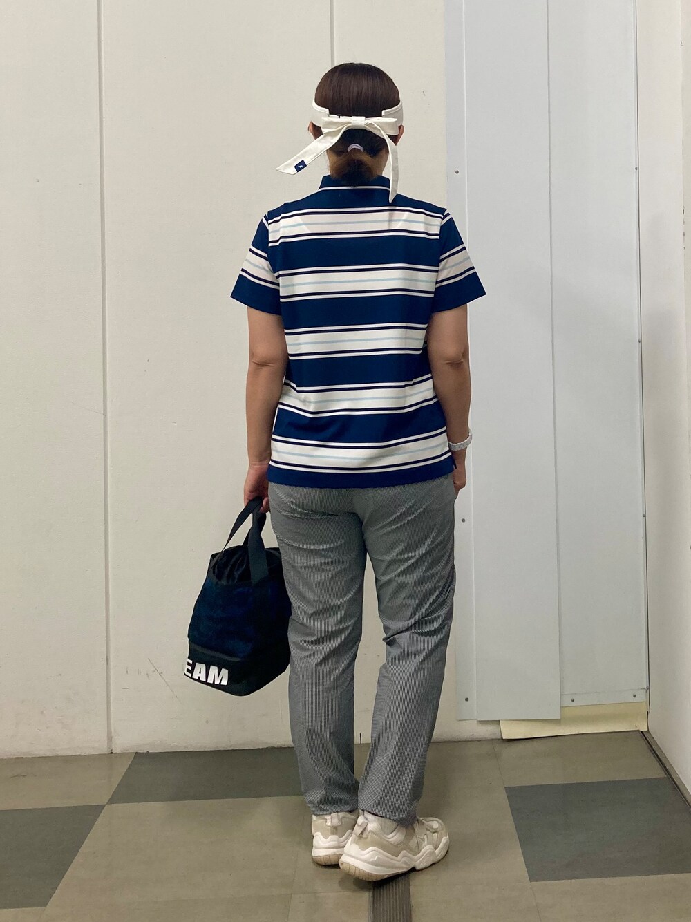 ブラック系のその他パンツ、ブルー系のトートバッグ、ブルー系のポロシャツを着用したレディースの夏コーディネートの3枚目の写真