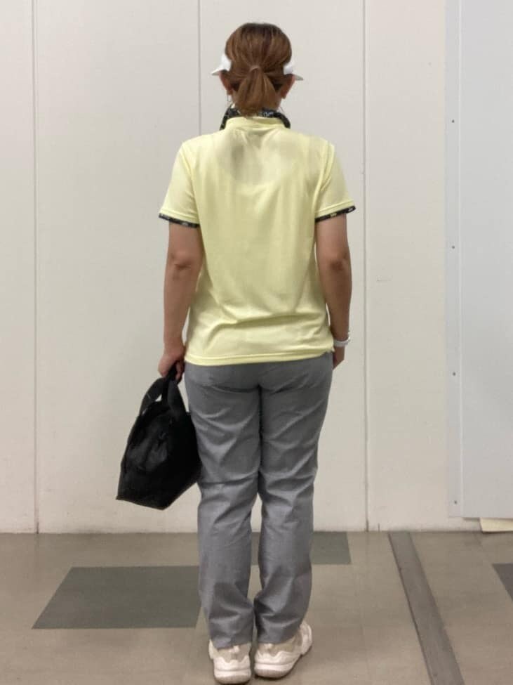 イエロー系のポロシャツ、ホワイト系のその他パンツ、ブラック系のハンドバッグを着用したレディースの春コーディネートの3枚目の写真