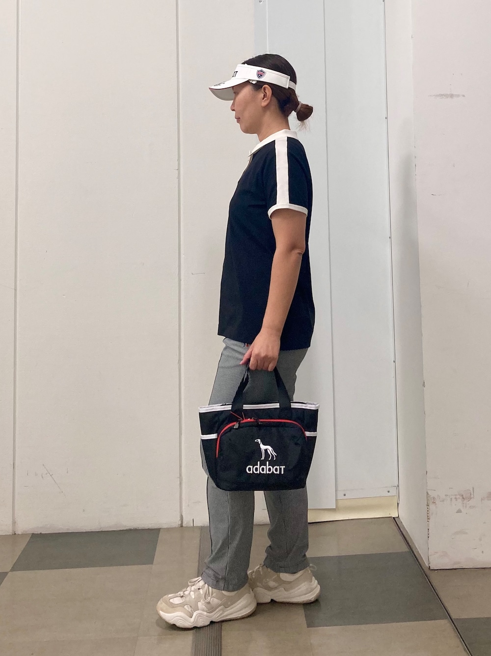 ブラック系のポロシャツ、ブラック系のその他パンツ、ブルー系のトートバッグを着用したレディースの春コーディネートの4枚目の写真