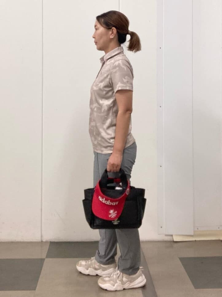 ベージュ系のポロシャツ、ブラック系のハンドバッグ、レッド系のサンバイザーを着用したレディースの夏コーディネートの4枚目の写真