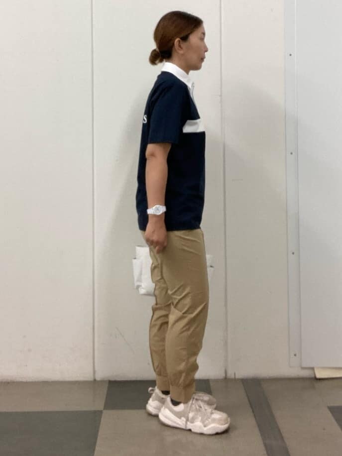 ブルー系のポロシャツ、ベージュ系のその他パンツ、ホワイト系のハンドバッグを着用したレディースの夏コーディネートの4枚目の写真
