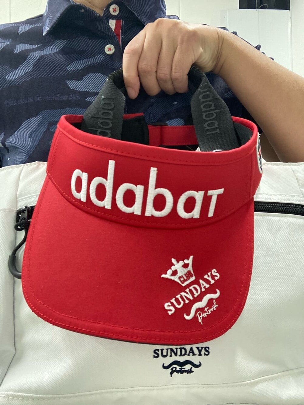ブルー系のポロシャツ、ホワイト系のハンドバッグ、レッド系のサンバイザーを着用したレディースの夏コーディネートの7枚目の写真