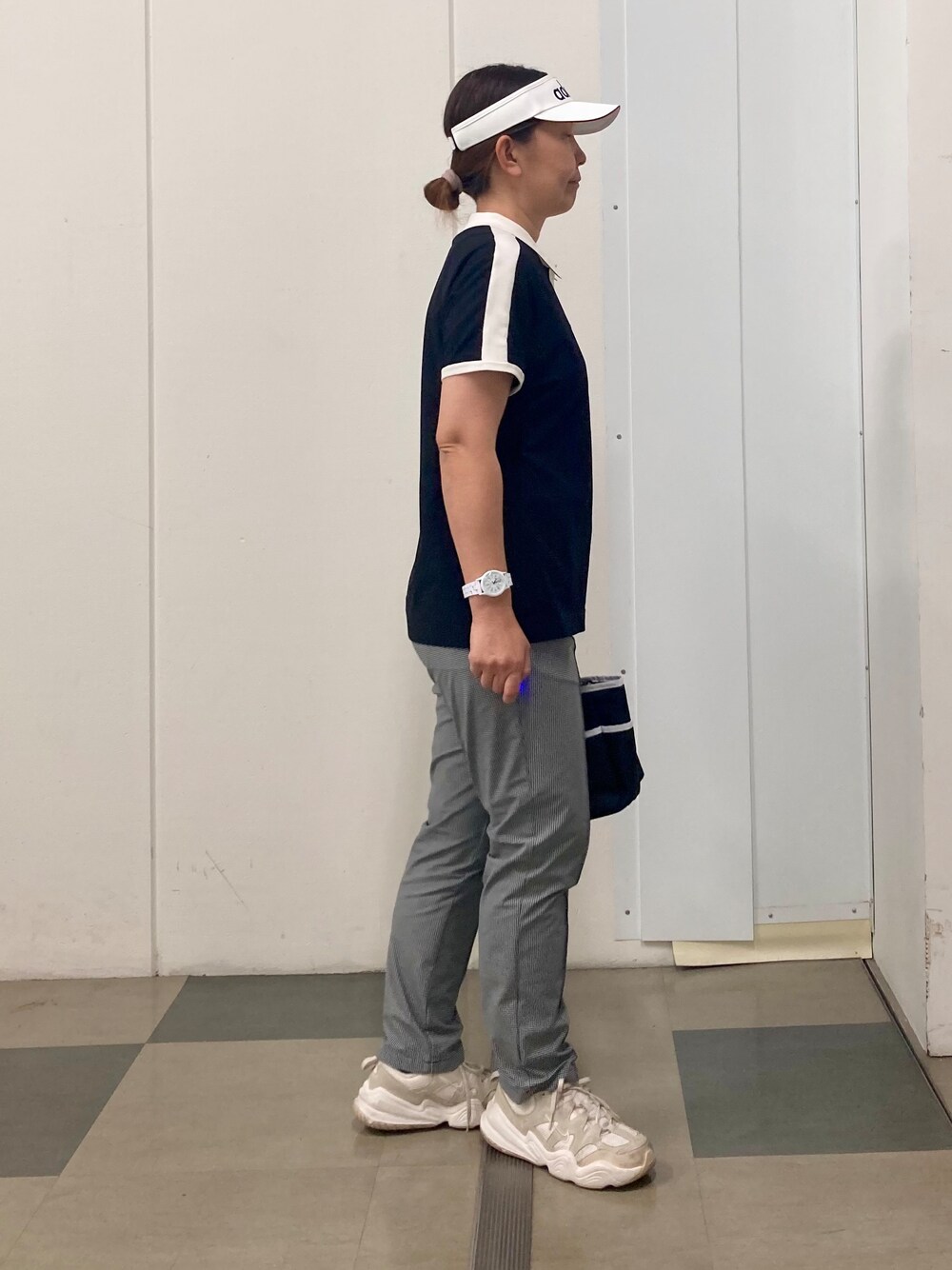 ブラック系のポロシャツ、ブラック系のその他パンツ、ブルー系のトートバッグを着用したレディースの春コーディネートの2枚目の写真