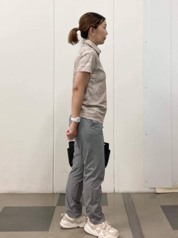 ベージュ系のポロシャツ、ブラック系のハンドバッグ、レッド系のサンバイザーを着用したレディースの夏コーディネートの2枚目の写真