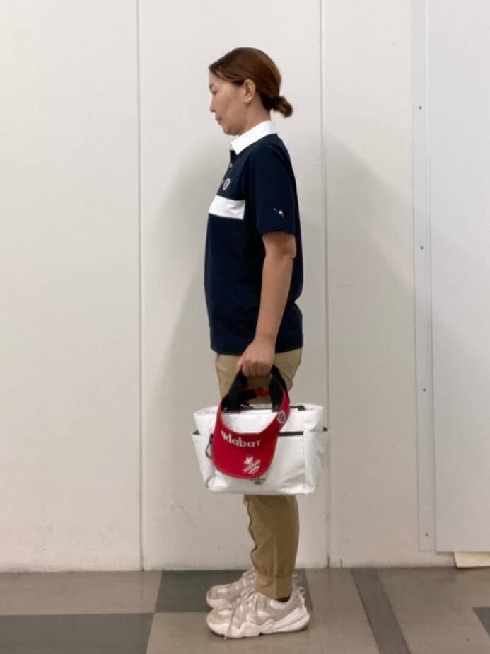 ブルー系のポロシャツ、ベージュ系のその他パンツ、ホワイト系のハンドバッグを着用したレディースの夏コーディネートの2枚目の写真