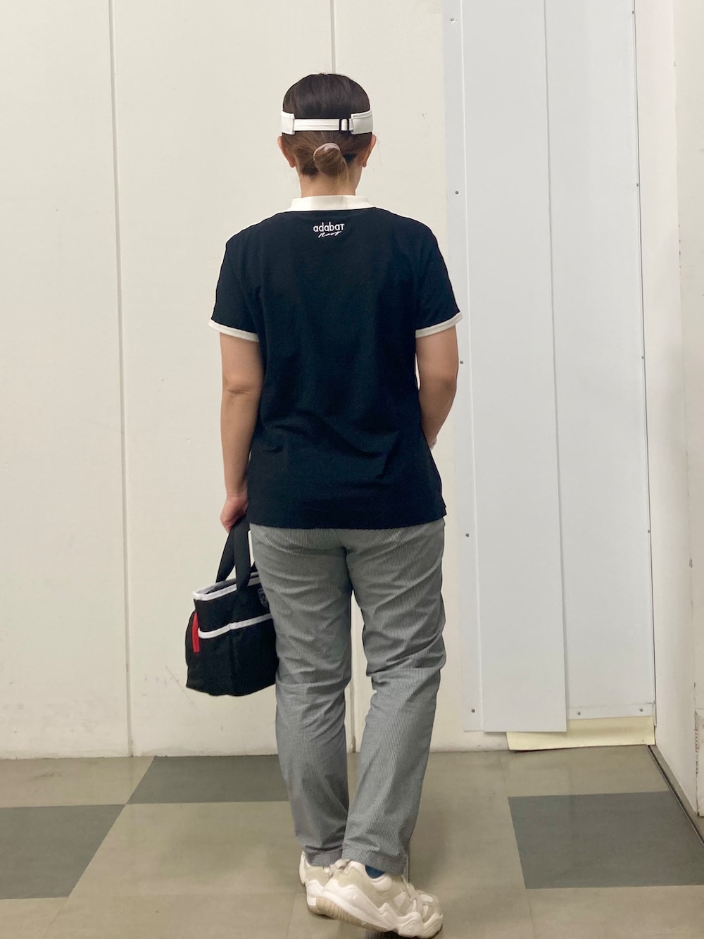 ブラック系のポロシャツ、ブラック系のその他パンツ、ブルー系のトートバッグを着用したレディースの春コーディネートの3枚目の写真