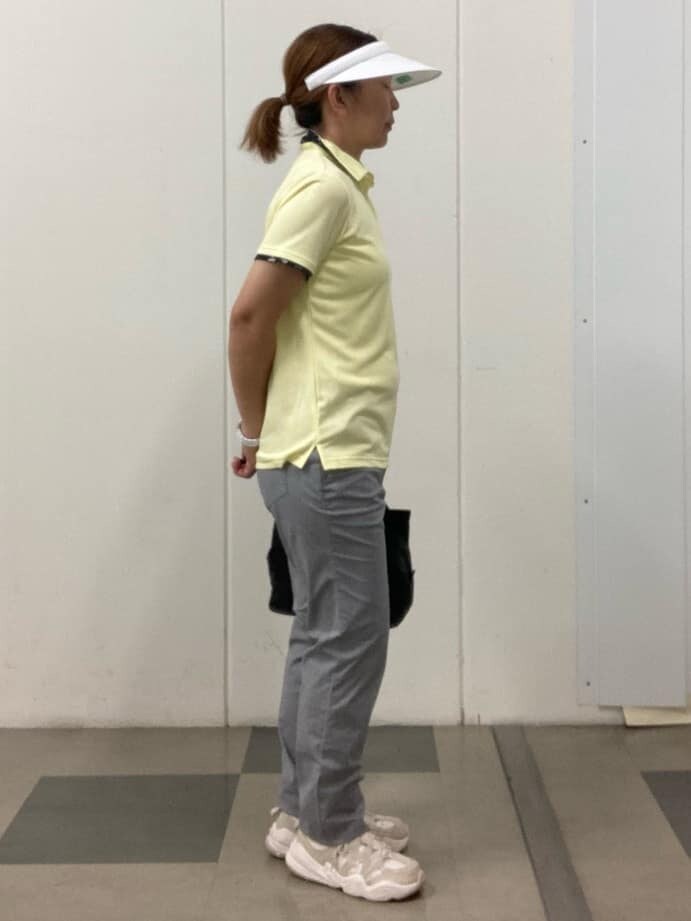 イエロー系のポロシャツ、ホワイト系のその他パンツ、ブラック系のハンドバッグを着用したレディースの春コーディネートの4枚目の写真