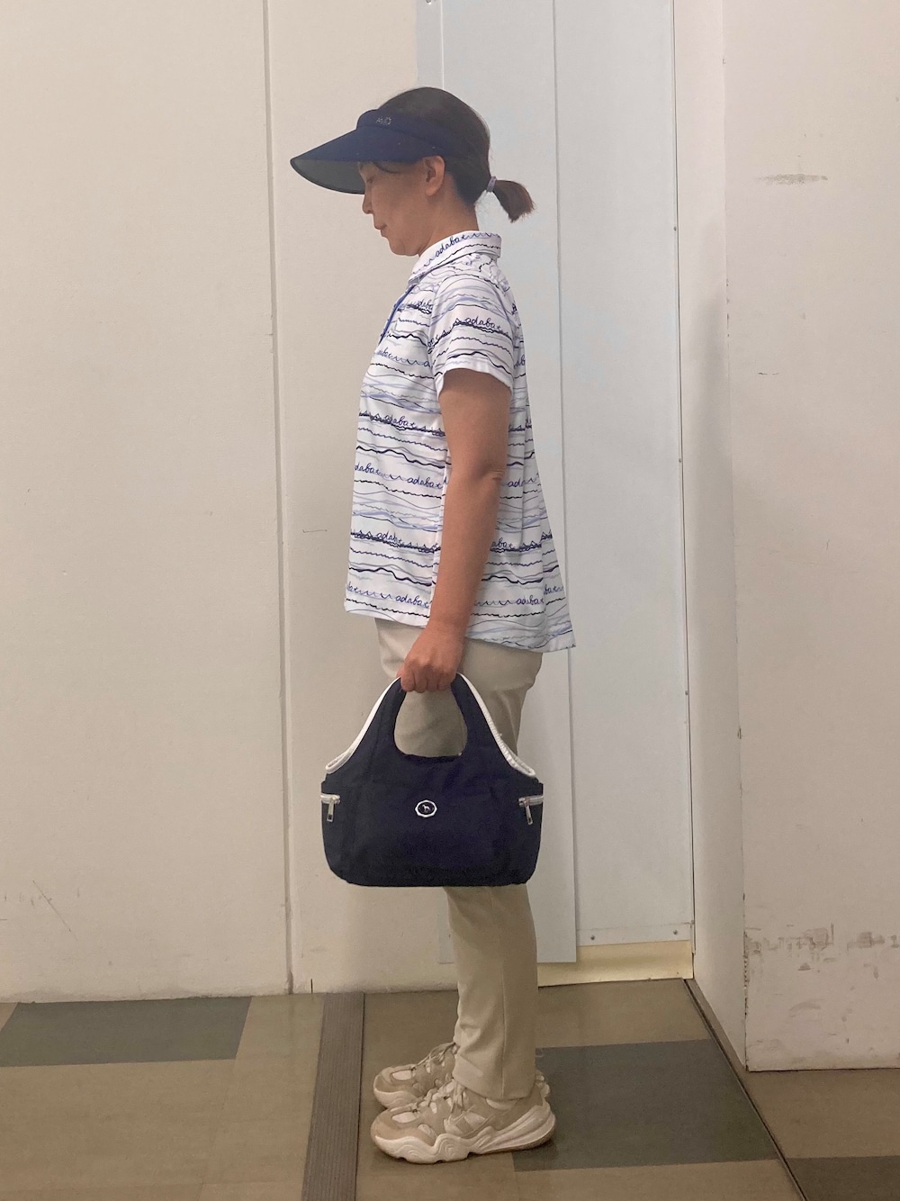 ブルー系のポロシャツ、ベージュ系のその他パンツ、ブルー系のサンバイザーを着用したレディースの夏コーディネートの3枚目の写真