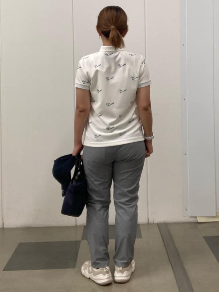 ホワイト系のポロシャツ、ブルー系のハンドバッグ、ブルー系のキャップを着用したレディースの春コーディネートの3枚目の写真