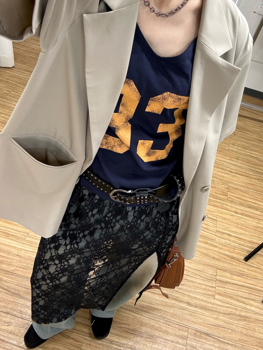 ブラック系のスカート、ブラック系のモカシン/デッキシューズ、ベージュ系のテーラードジャケットを着用したレディースの春コーディネートの2枚目の写真