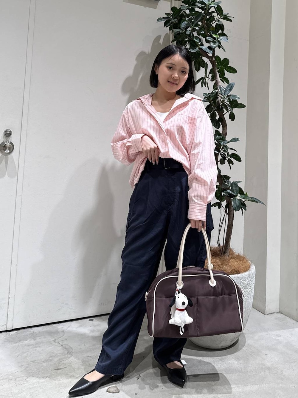 ブラウン系のボストンバッグ、ブラック系のパンプス、ブルー系のカーゴパンツを着用したレディースの春コーディネートの2枚目の写真