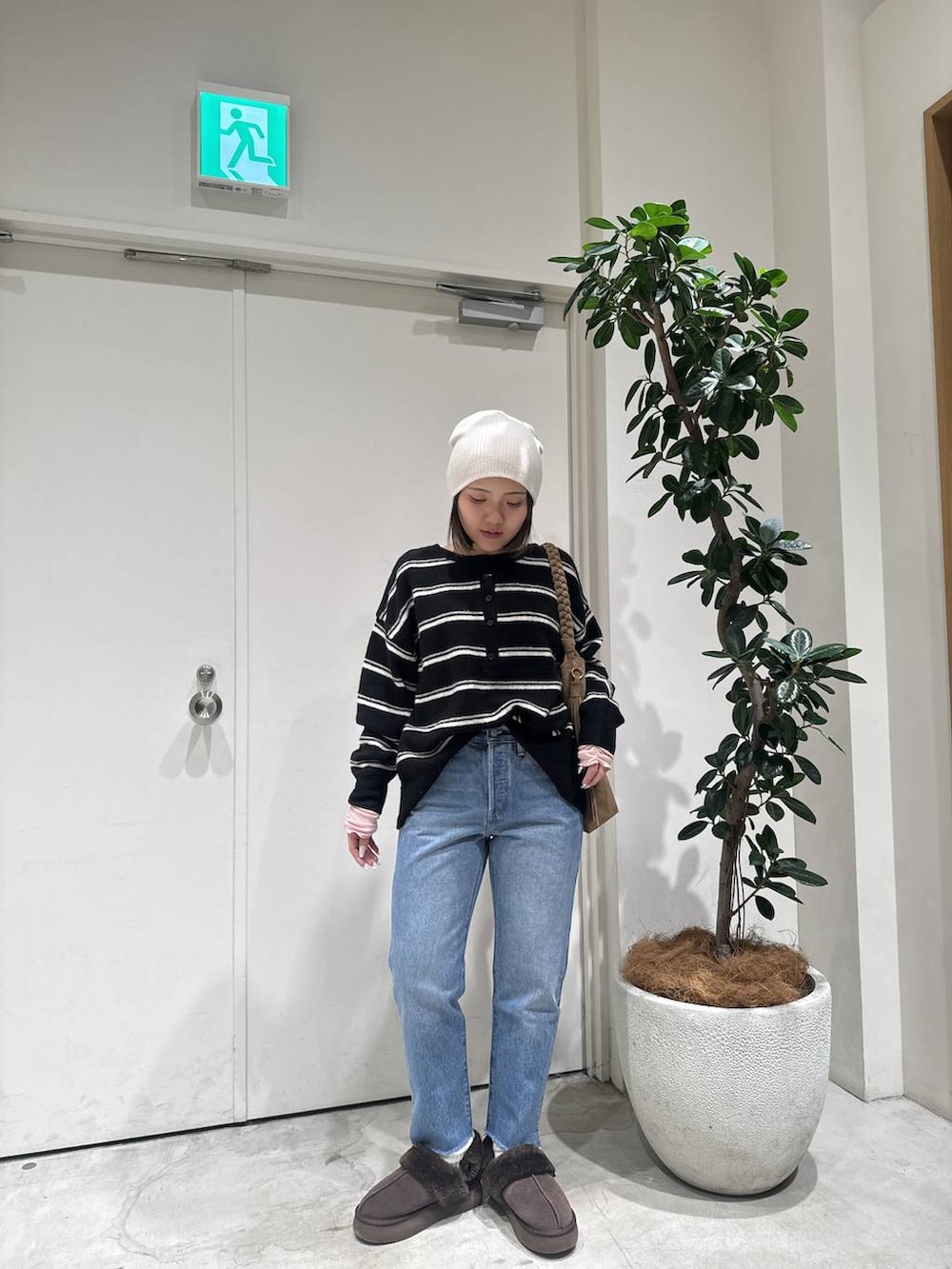 ブラウン系のトートバッグ、ブルー系のデニムパンツ、ブラック系のニット/セーターを着用したレディースの冬コーディネートの4枚目の写真