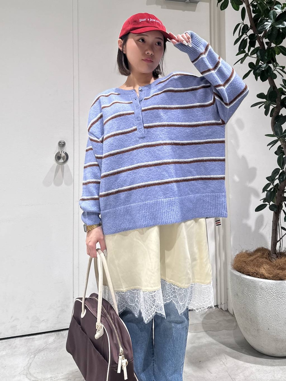 ブルー系のデニムパンツ、ブラウン系のボストンバッグ、ブルー系のニット/セーターを着用したレディースの冬コーディネートの3枚目の写真