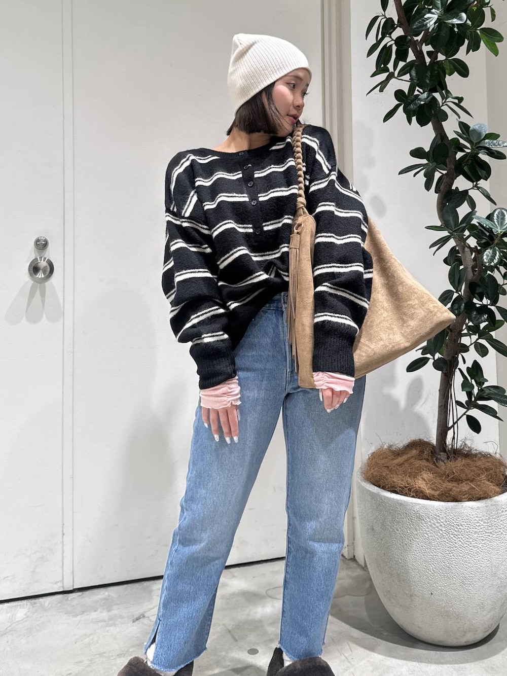 ブラウン系のトートバッグ、ブルー系のデニムパンツ、ブラック系のニット/セーターを着用したレディースの冬コーディネートの3枚目の写真