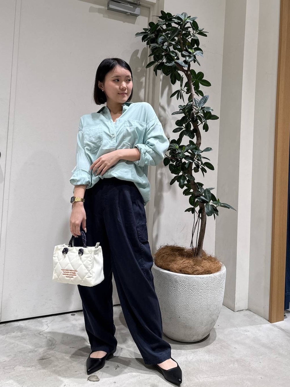 グリーン系のシャツ/ブラウス、ブラック系のパンプス、ホワイト系のショルダーバッグを着用したレディースの春コーディネートの4枚目の写真