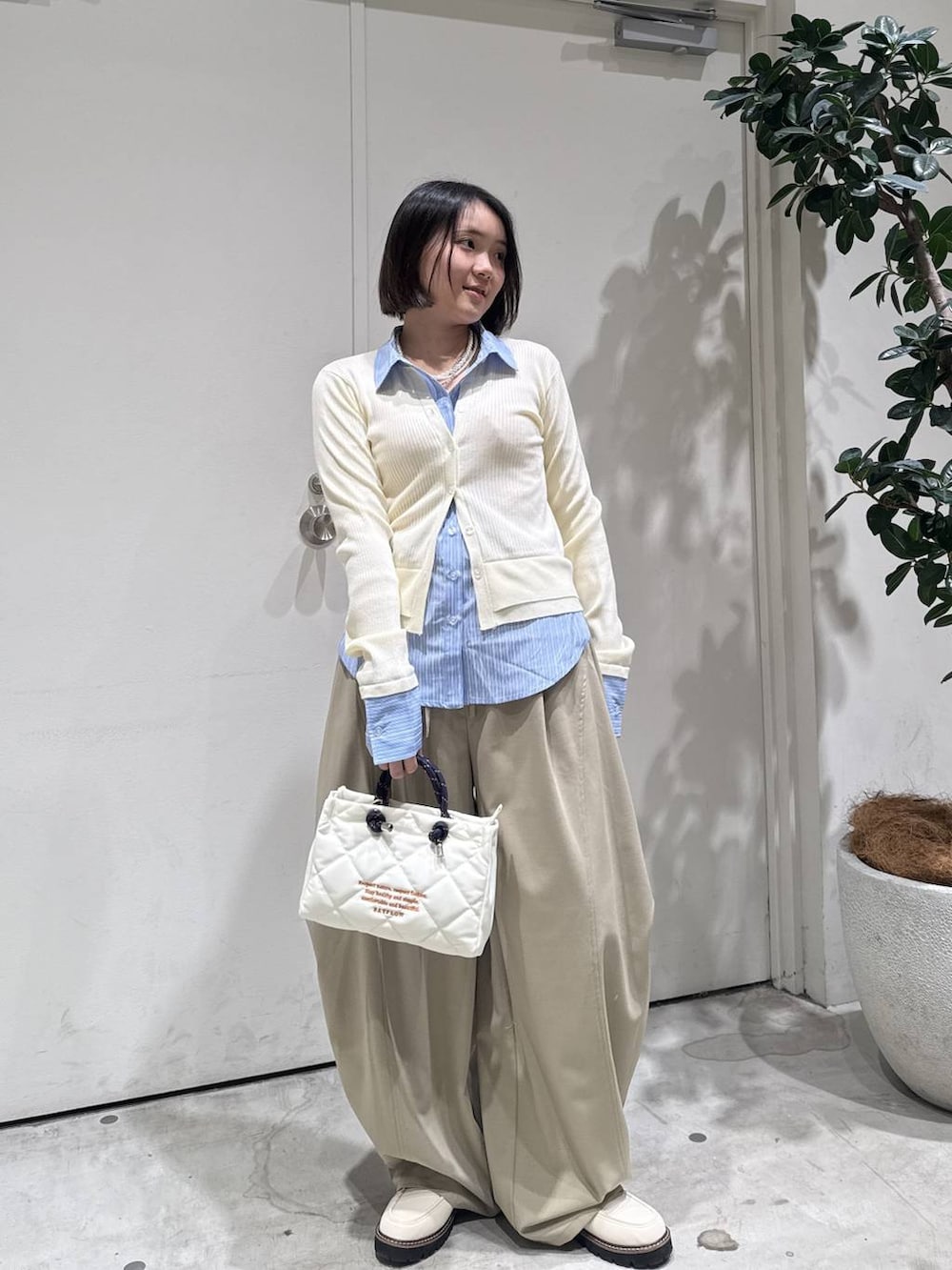 ホワイト系のローファー、ベージュ系のその他パンツ、ホワイト系のショルダーバッグを着用したレディースの冬コーディネートの2枚目の写真