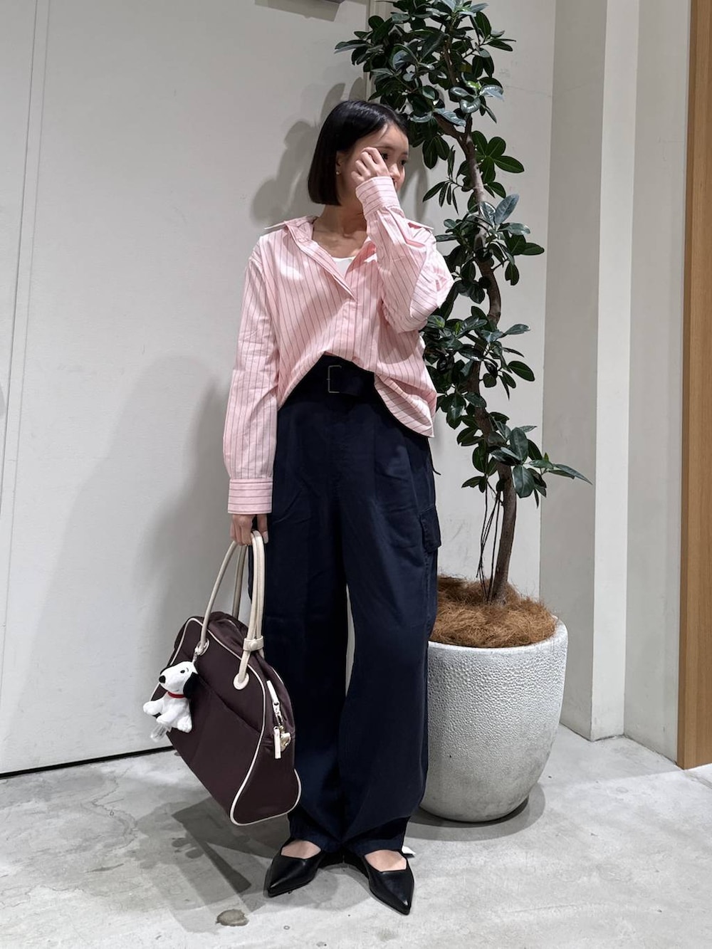 ブラウン系のボストンバッグ、ブラック系のパンプス、ブルー系のカーゴパンツを着用したレディースの春コーディネートの3枚目の写真