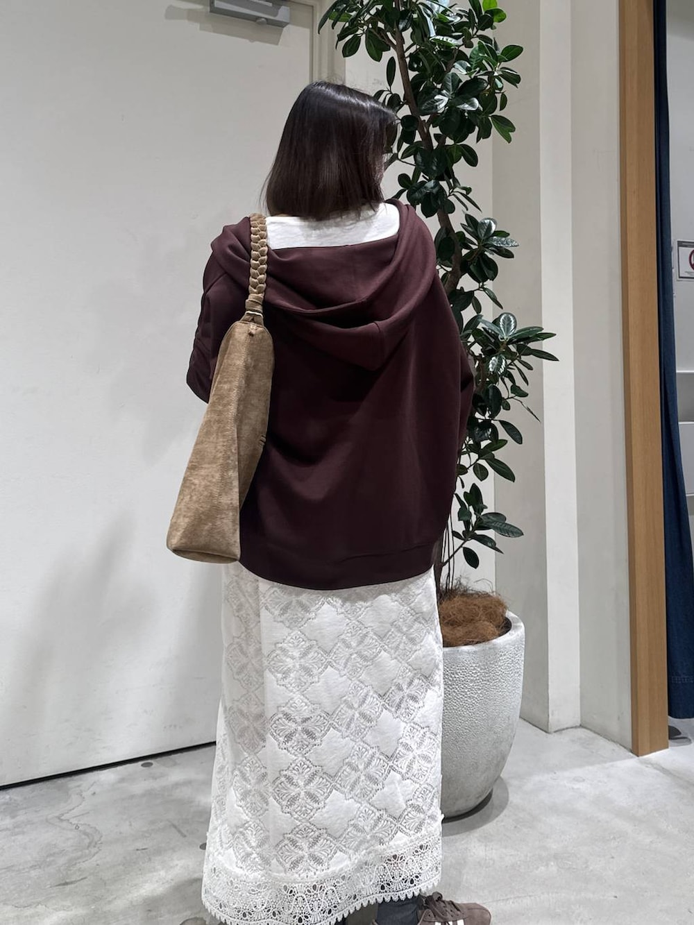 ブラウン系のパーカー、ホワイト系のスカートを着用したレディースの冬コーディネートの2枚目の写真