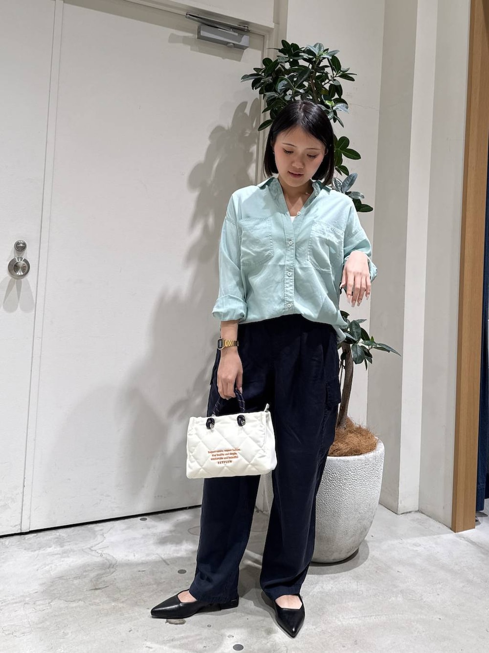 グリーン系のシャツ/ブラウス、ブラック系のパンプス、ホワイト系のショルダーバッグを着用したレディースの春コーディネートの2枚目の写真