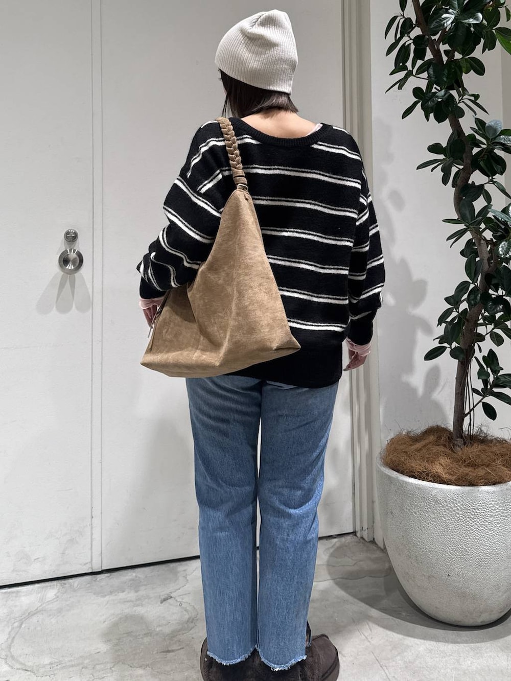 ブラウン系のトートバッグ、ブルー系のデニムパンツ、ブラック系のニット/セーターを着用したレディースの冬コーディネートの2枚目の写真