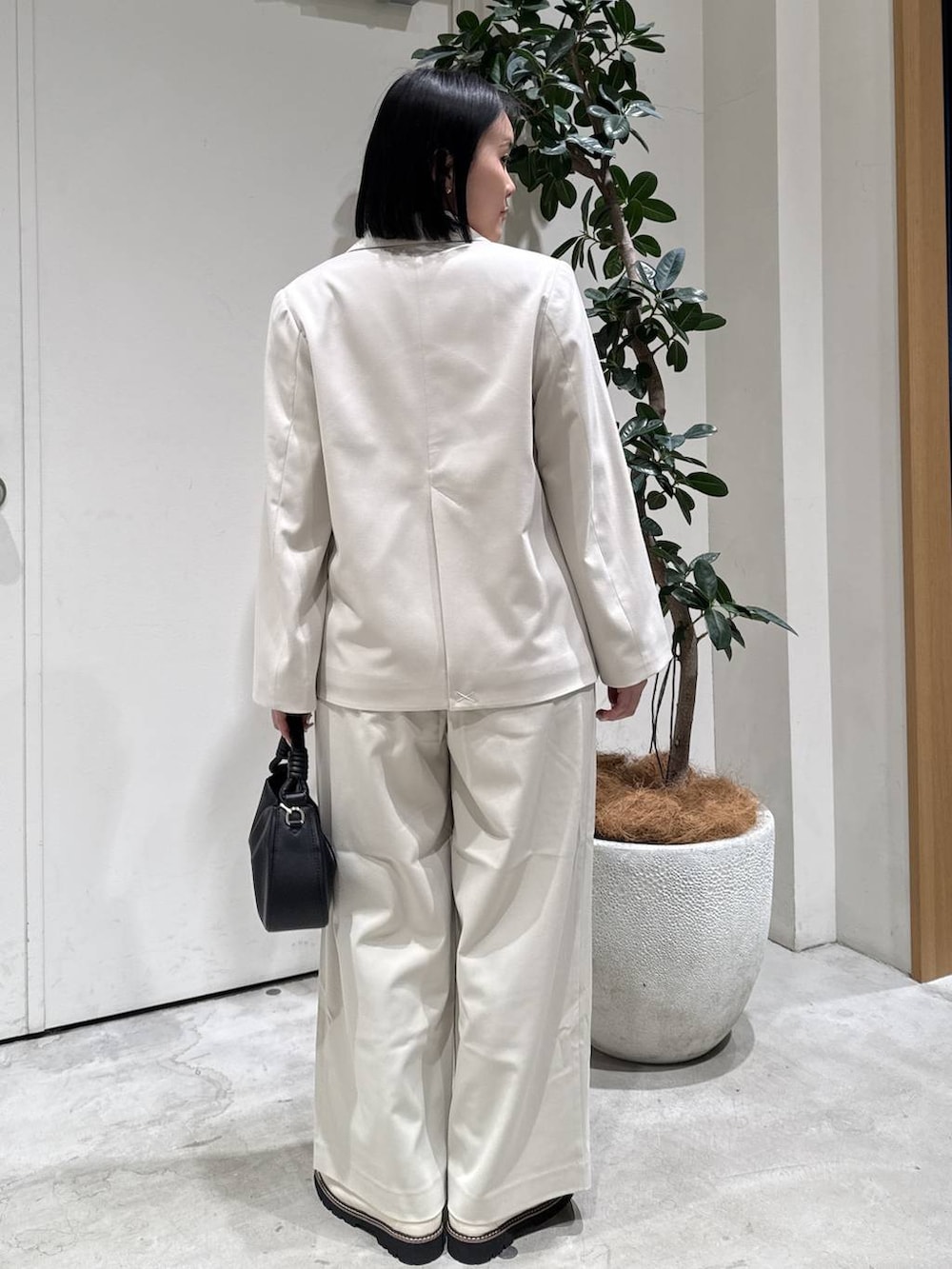 ベージュ系のテーラードジャケット、ベージュ系のスラックス、ブラック系のハンドバッグを着用したレディースの冬コーディネートの2枚目の写真