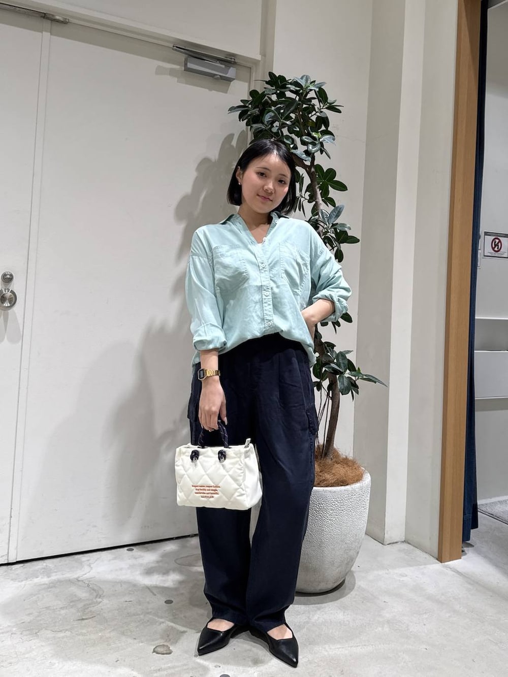 グリーン系のシャツ/ブラウス、ブラック系のパンプス、ホワイト系のショルダーバッグを着用したレディースの春コーディネートの3枚目の写真