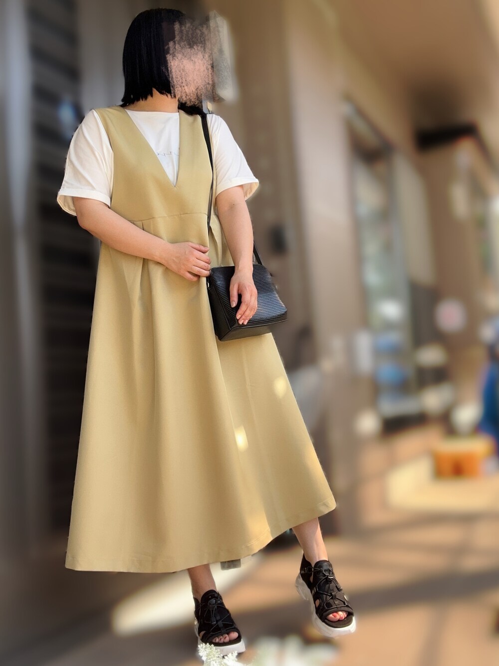 ブラック系のバッグ、イエロー系のワンピース/ドレス、ブラック系のサンダルを着用したレディースの夏コーディネートの2枚目の写真