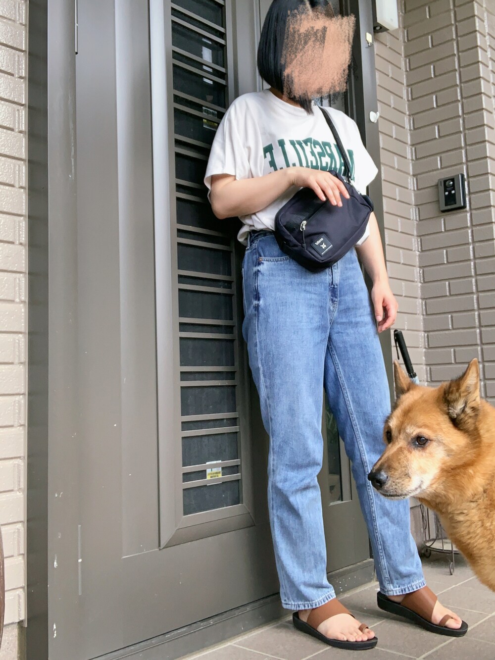 ブラック系のショルダーバッグ、ブルー系のデニムパンツを着用したレディースの夏コーディネートの2枚目の写真