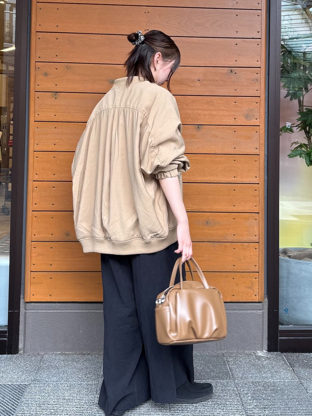 イエロー系のショルダーバッグ、ベージュ系のブルゾン、ブラック系のスラックスを着用したレディースの春コーディネートの2枚目の写真