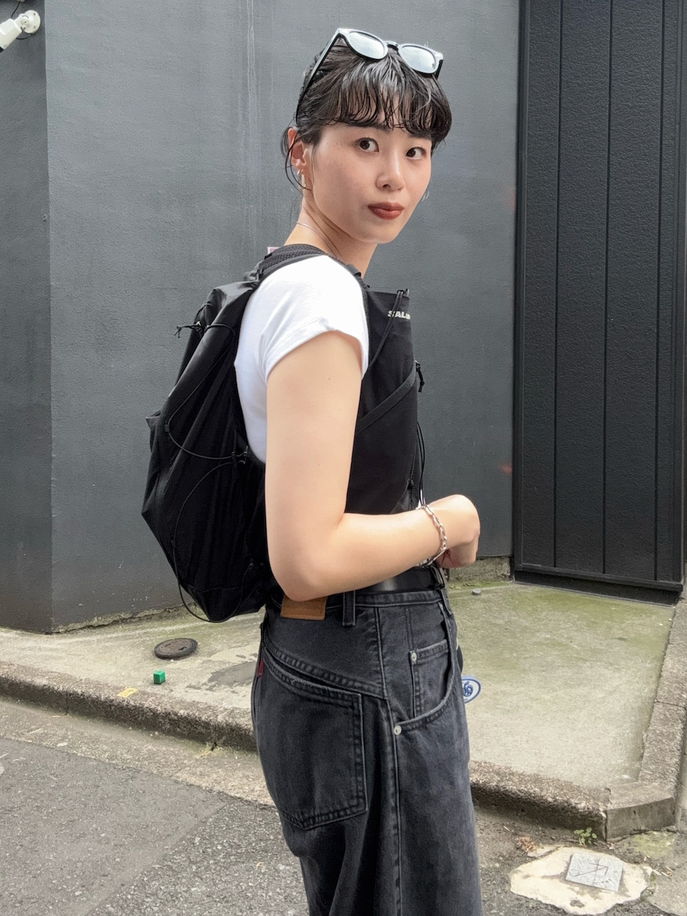 ホワイト系のTシャツ/カットソー、ブラック系のデニムパンツ、ブラック系のバックパック/リュックを着用したレディースの夏コーディネートの2枚目の写真