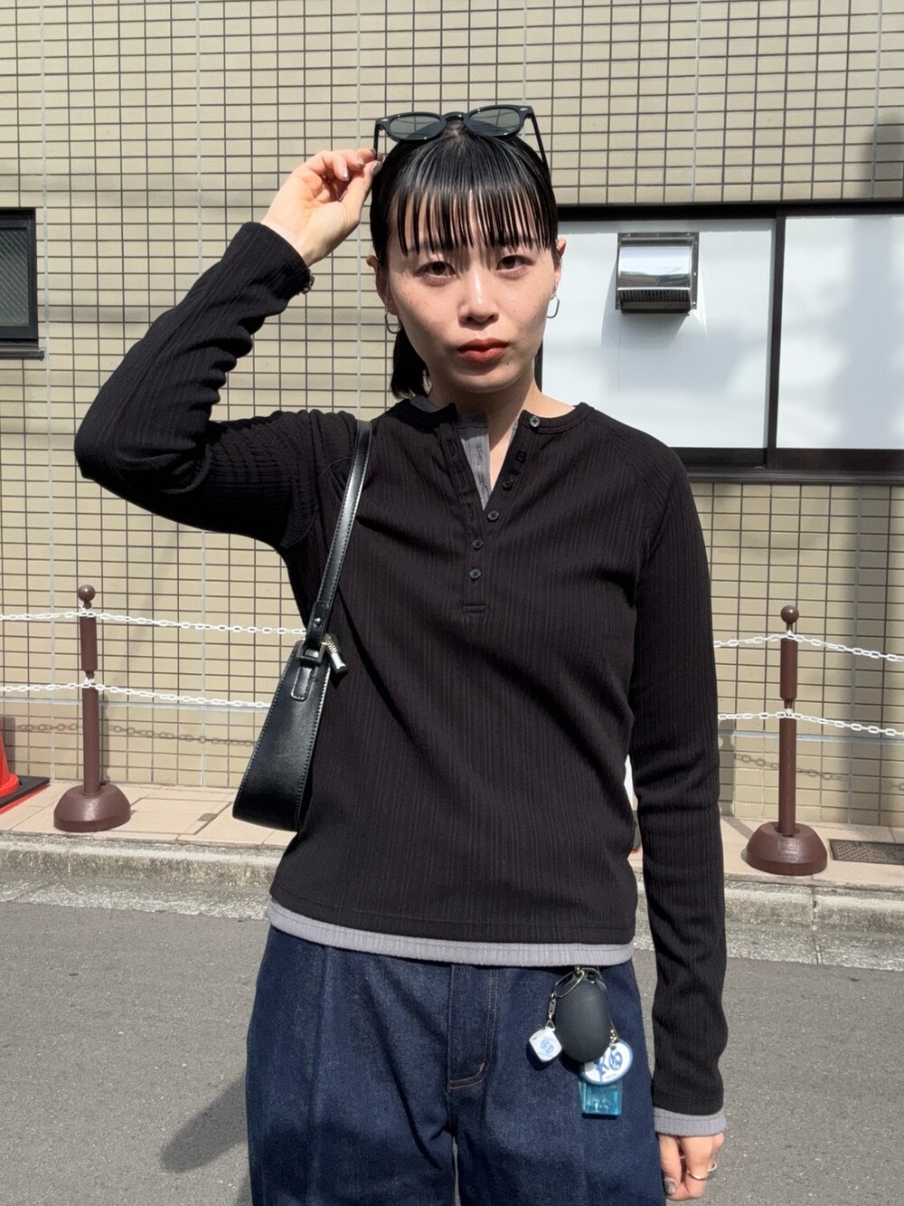ブラック系のトップス、ブルー系のデニムパンツ、ブラック系のショルダーバッグを着用したレディースの夏コーディネートの3枚目の写真
