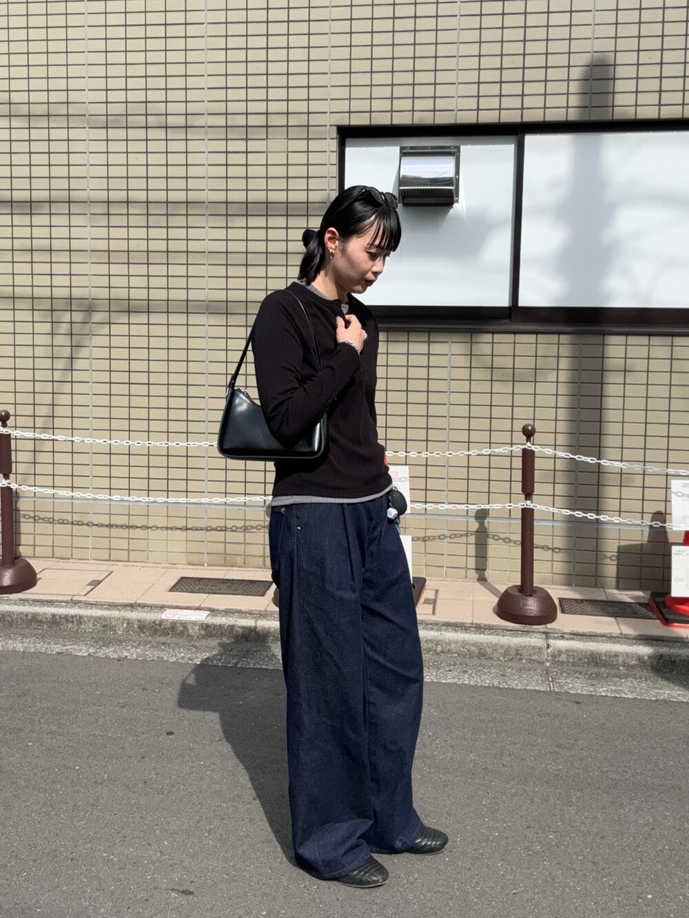 ブラック系のトップス、ブルー系のデニムパンツ、ブラック系のショルダーバッグを着用したレディースの夏コーディネートの2枚目の写真