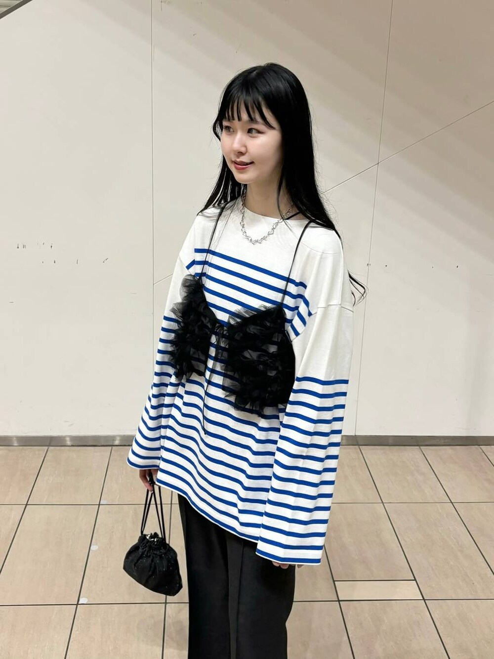 グレー系のスラックス、ブラック系のブーツ、ブラック系のショルダーバッグを着用したレディースの秋コーディネートの3枚目の写真