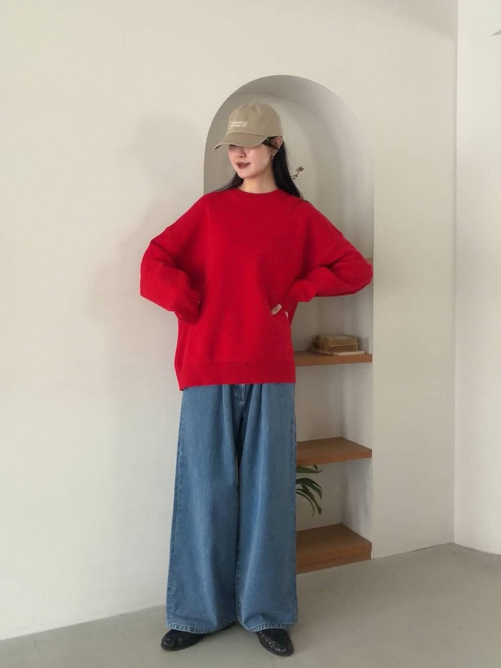 レッド系のニット/セーター、ブルー系のデニムパンツを着用したレディースの冬コーディネートの2枚目の写真