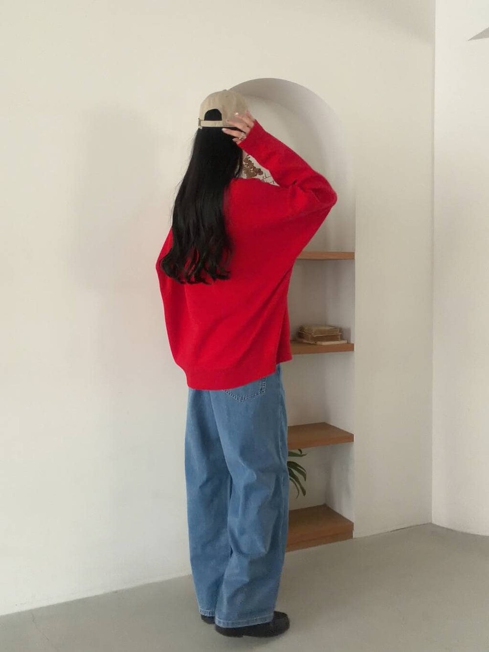 レッド系のニット/セーター、ブルー系のデニムパンツを着用したレディースの冬コーディネートの3枚目の写真